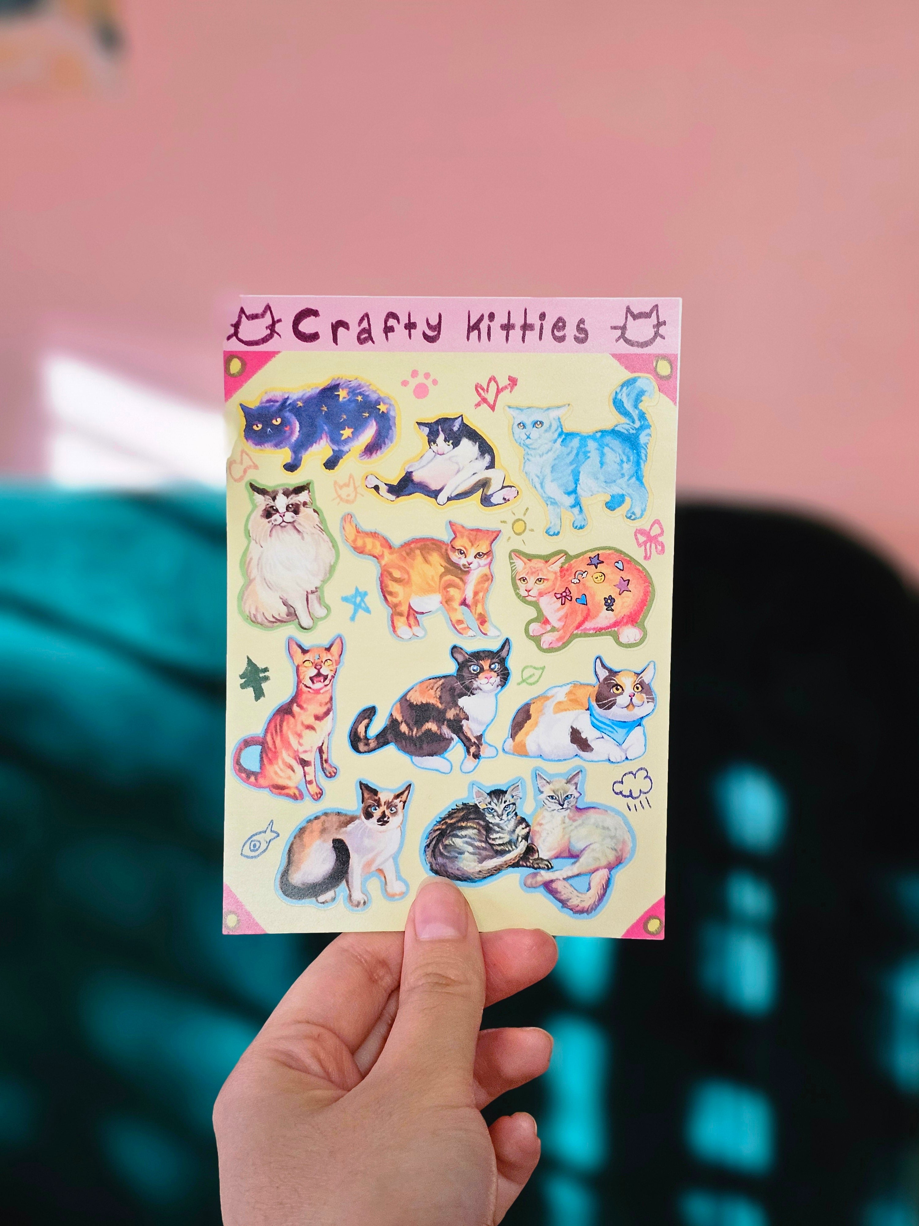 Sheet of cat-themed sticker sheets held by a hand with a colorful background