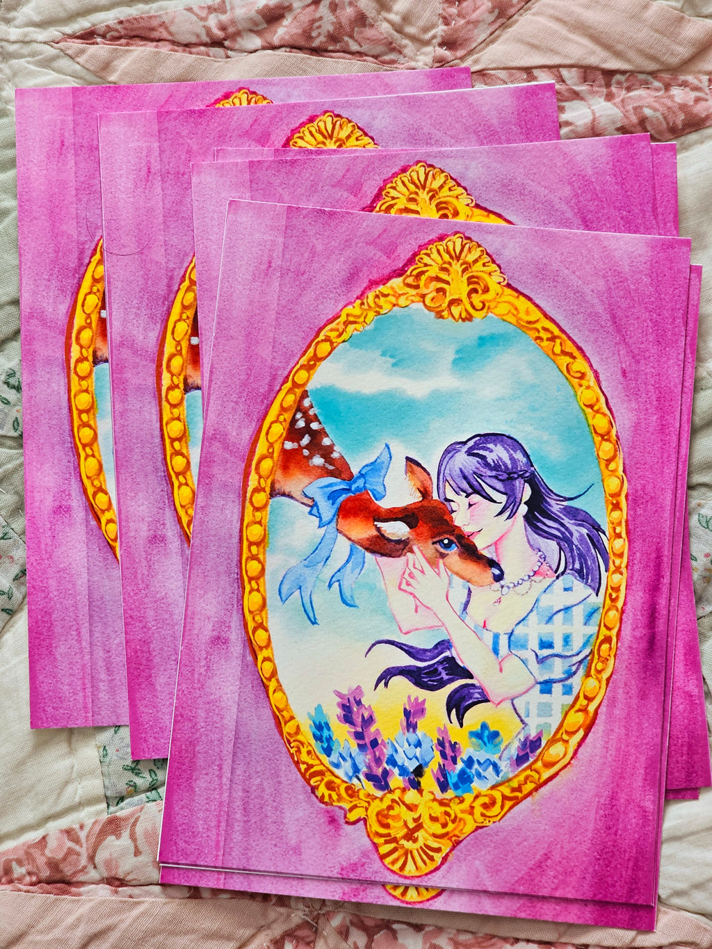 Multiple postcards with a girl and deer illustration on a floral fabric background