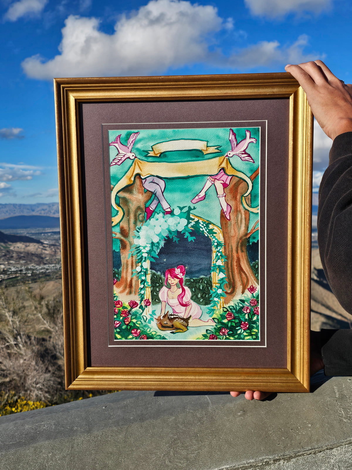 Framed artwork of a woman under a floral arch against a blue sky.